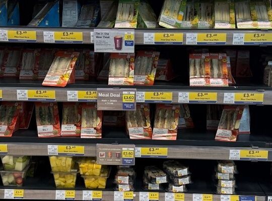 Retail food-to-go fixture showing a variety of sandwiches and snacks across UK supermarkets.