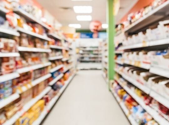 Food and drink supplier reviewing category data on a tablet in a retail aisle.