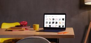 Laptop on a desk with multiple content designs open and a coffee nearby, representing content marketing strategies that take time but don’t always bring in clients