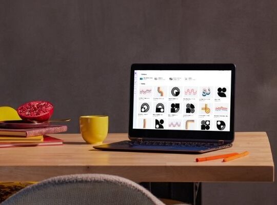 Laptop on a desk with multiple content designs open and a coffee nearby, representing content marketing strategies that take time but don’t always bring in clients