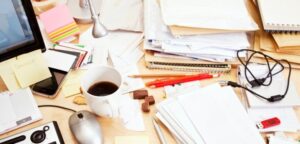 Messy desk with laptop, sticky notes and phone notifications showing scattered marketing activity and lack of focus.