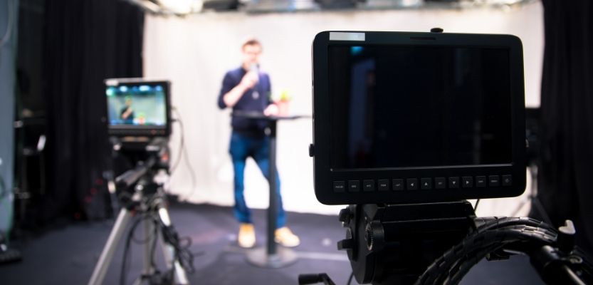 Business owner filming a professional marketing video with camera on tripod.